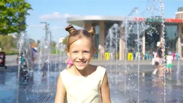 Niña adorable divertirse en la fuente de la calle en el día soleado caliente — Vídeos de Stock