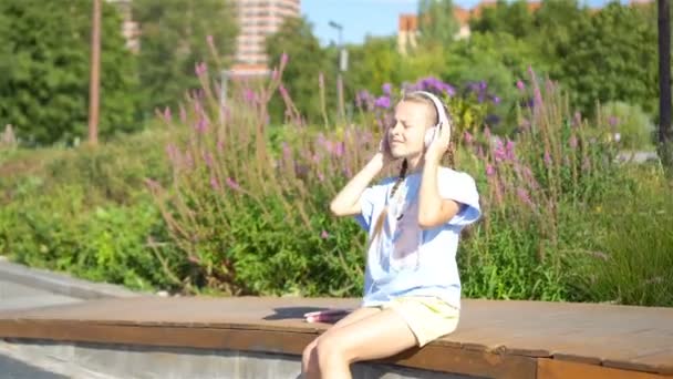 屋外の公園で小さな愛らしい少女音楽を聴く — ストック動画