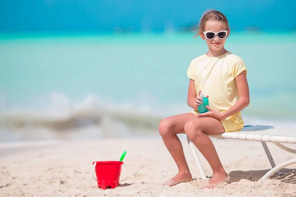 Beautiful kid with bottle of sun cream on tropical beach — Stock Photo, Image