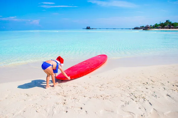Niña en el sombrero de Santa durante las vacaciones de playa en vacaciones tropicales —  Fotos de Stock