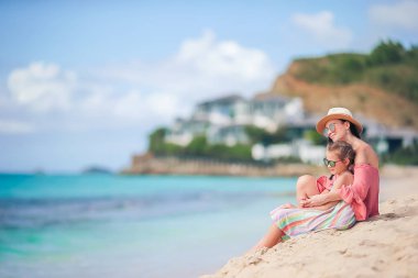 Tropikal sahilde küçük tatlı bir kız ve genç bir anne.