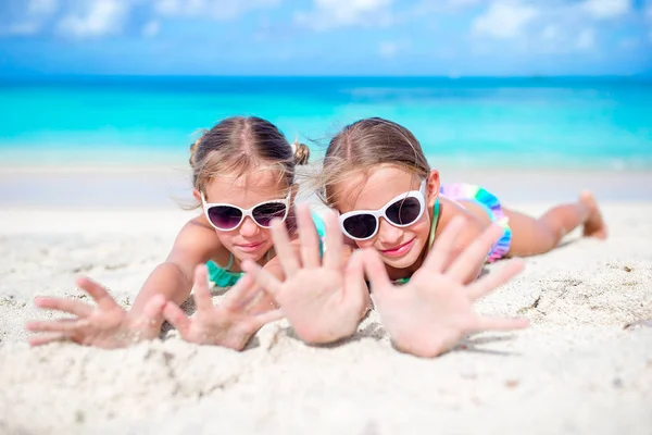 A kislányok jól érzik magukat a trópusi strandon, együtt játszanak a sekély vízben. Imádnivaló kis nővérek a strandon a nyári vakáció alatt — Stock Fotó