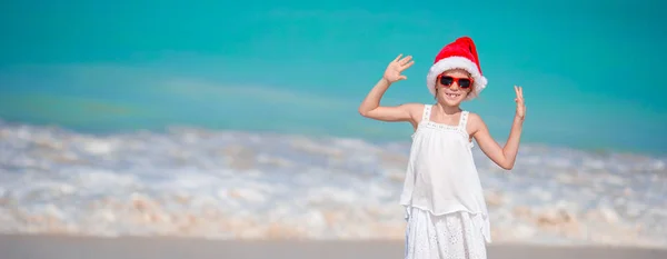 Adorable little girl in Santa hat on tropical beach — Stock Photo, Image