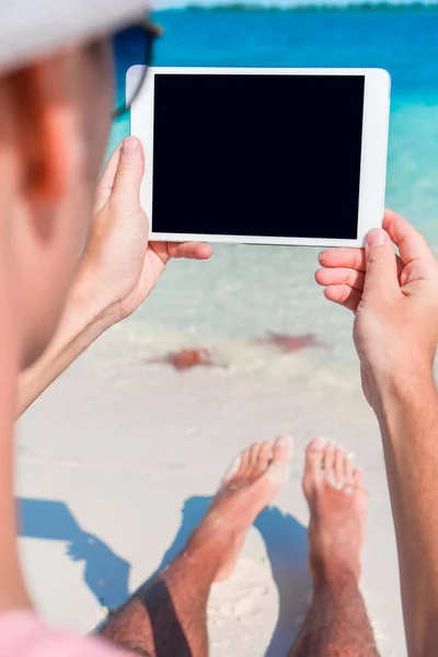 Hombre joven con portátil en el fondo del océano turquesa en la playa tropical — Foto de Stock