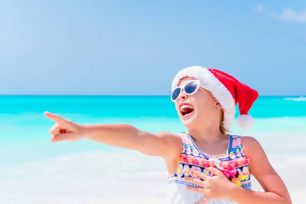 Felice divertente bambina a Babbo Natale cappello durante le vacanze al mare di Natale hanno un sacco di divertimento — Foto Stock