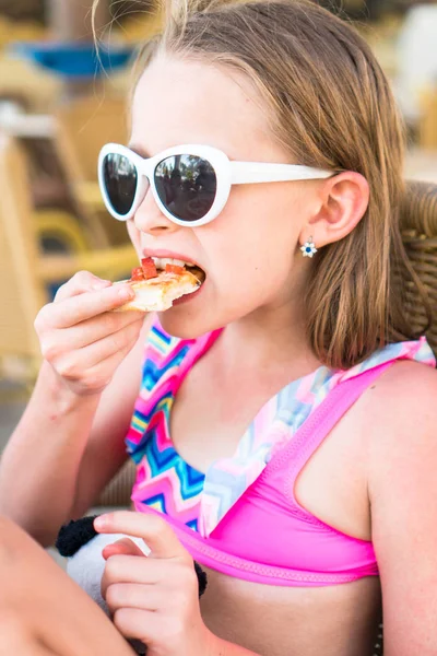 Портрет маленькой девочки, которая ест пиццу в кафе на открытом воздухе за ужином — стоковое фото