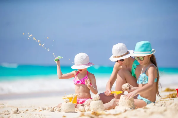 Matka i małe córeczki robiące zamek z piasku na tropikalnej plaży — Zdjęcie stockowe