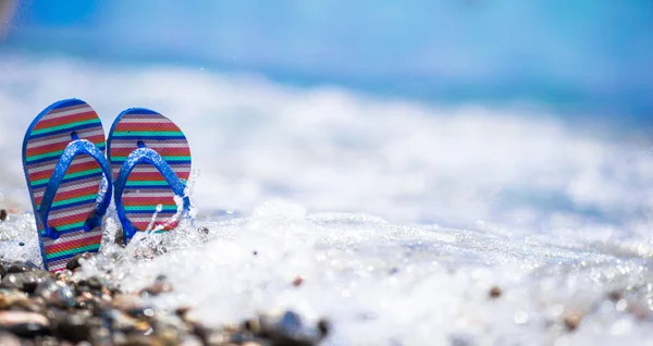 Blue flip flops on beach in front of the sea — Stock Photo, Image