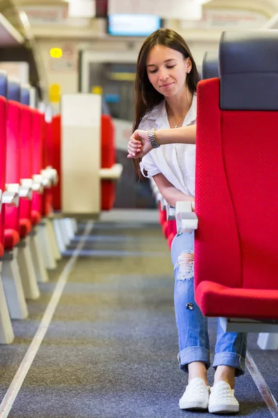 Junges glückliches Mädchen schaut auf Uhr, die mit dem Zug reist — Stockfoto