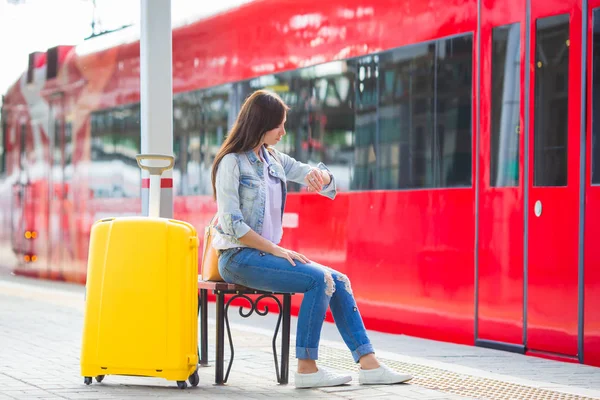 Ung vacker flicka med bagage vid en järnvägsstation — Stockfoto