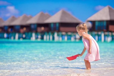 Turkuaz denizde origami tekne ile oynarken sevimli küçük kız