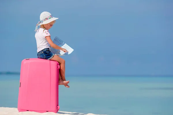 Little tourists girl with big suitcase on tropical white beach — Stock Photo, Image