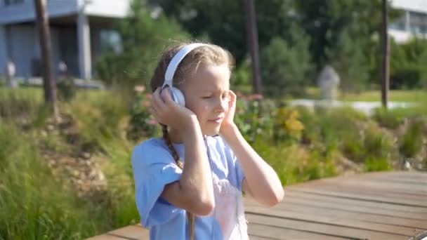 Parkta müzik dinleyen küçük sevimli kız. — Stok video