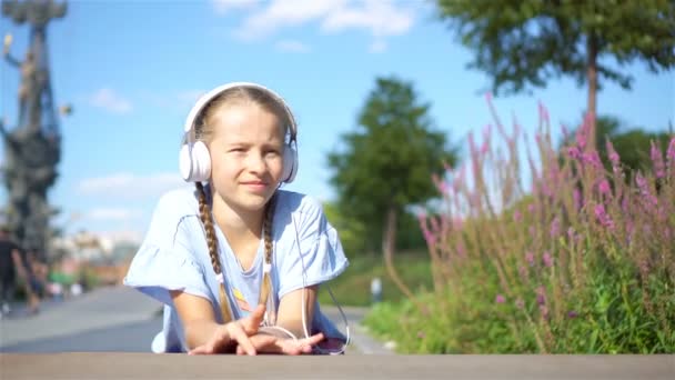 Parkta müzik dinleyen küçük sevimli kız. — Stok video