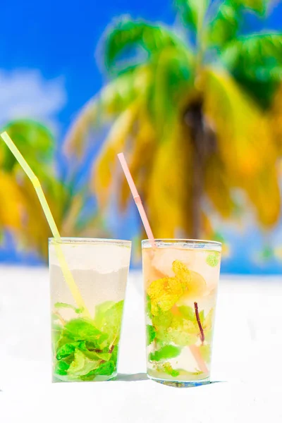 Two cold tasty mohito cocktails on the white sandy beach in palm grove — Stock Photo, Image