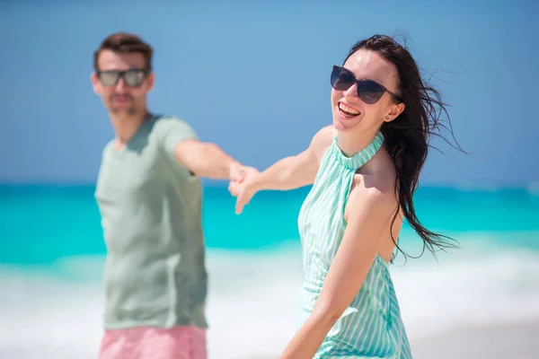 Улыбающаяся пара, держащаяся за руки на пляже — стоковое фото