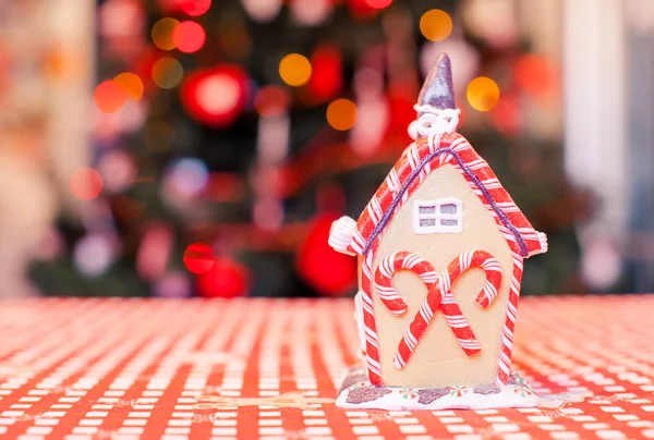Casa de hadas de jengibre decorada con dulces de colores sobre un fondo de brillante árbol de Navidad con guirnalda — Foto de Stock
