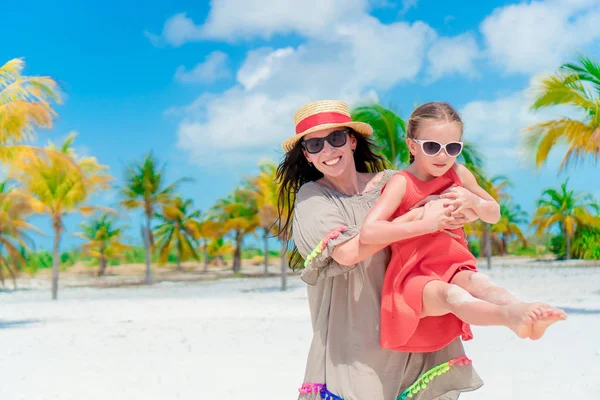 Liten söt flicka och ung mor på tropisk strand — Stockfoto