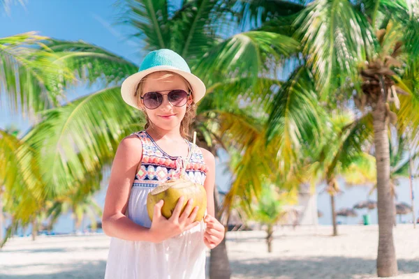 Kleines entzückendes Mädchen mit großer Kokosnuss am weißen Sandstrand — Stockfoto