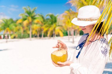 Genç kadın Hindistan cevizi sütü sıcak gün sahilde içme..