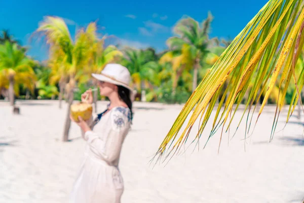 Mujer joven bebiendo leche de coco en un día caluroso en la playa . — Foto de Stock