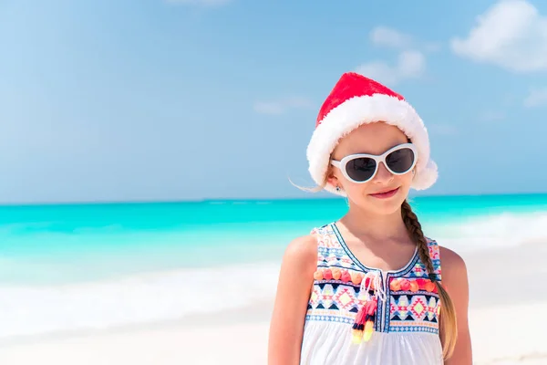 Schattig klein meisje in Santa hoed tijdens kerstvakantie strand — Stockfoto