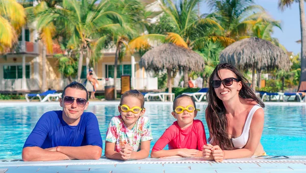 Família jovem com duas crianças desfrutar de férias de verão na piscina exterior — Fotografia de Stock