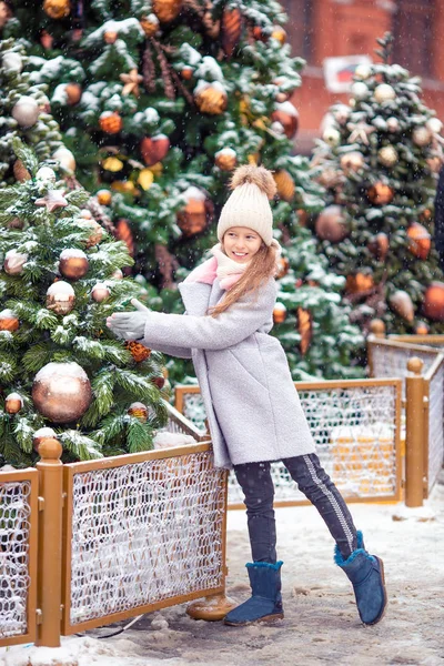 Маленькая счастливая девочка у елки ветки в снегу на Новый год . — стоковое фото