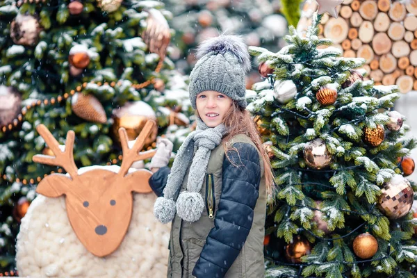 Little happy girl near fir-tree branch in snow for new year. — Stock Photo, Image