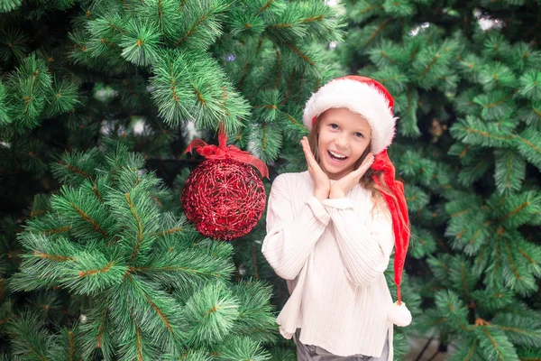 Gadis kecil yang bahagia dekat cabang pohon cemara di salju untuk tahun baru . — Stok Foto