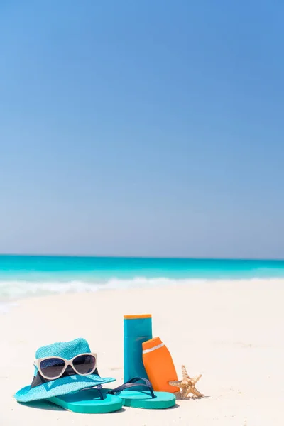 Garrafas de creme solar, óculos, estrelas do mar e óculos de sol no fundo da praia de areia branca oceano — Fotografia de Stock