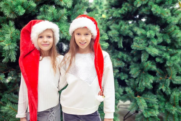 Little happy girls near fir-tree branch in snow for new year. — Stock Photo, Image