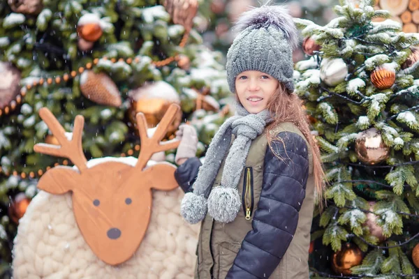 Yeni yıl için kar köknar ağacı dalında yakınındaki küçük mutlu kız. — Stok fotoğraf