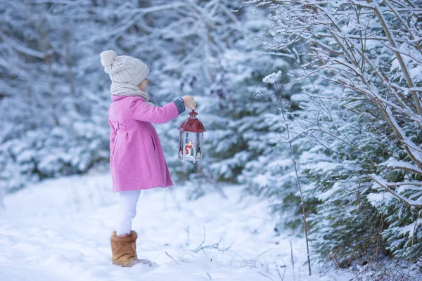 Adorable little girl with flashlight on Christmas at winter forest outdoors — Stock Photo, Image