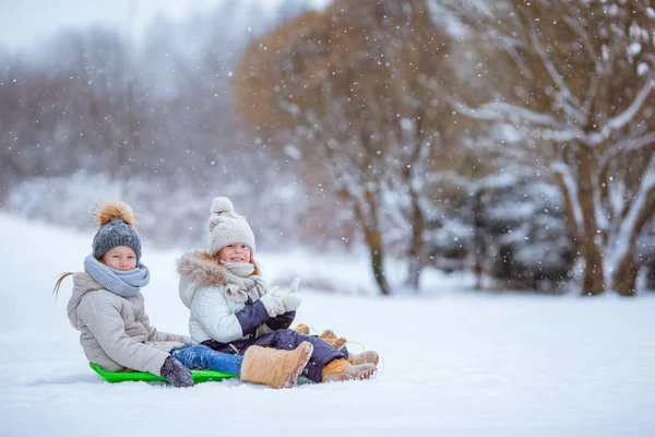 Adorable little happy girls sledding in winter snowy day. — Stock Photo, Image