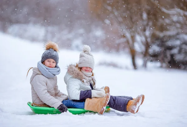 Adorable little happy girls sledding in winter snowy day. — Stock Photo, Image