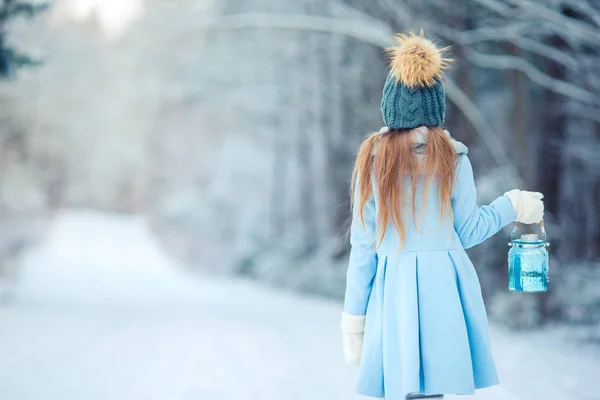 Bedårande liten flicka med ficklampa på jul på winter forest utomhus — Stockfoto