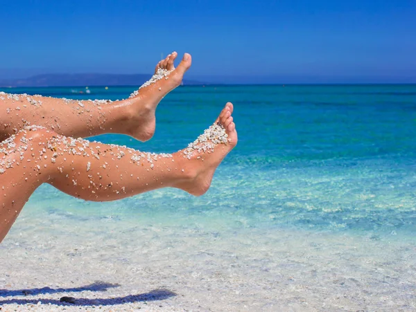Close-up van vrouwelijke benen achtergrond van de turquoise zee — Stockfoto