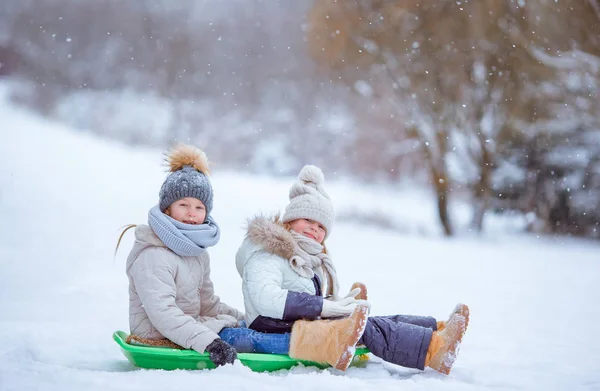 Adorable poco feliz niñas trineo en invierno nevado día . — Foto de Stock