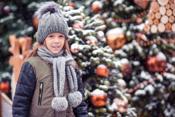 Little happy girl near fir-tree branch in snow for new year. — Stock Photo, Image