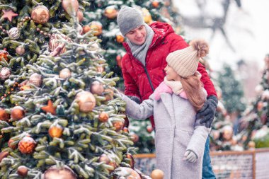 Yeni yıl için kar köknar ağacı dalında yakınındaki küçük mutlu kız.