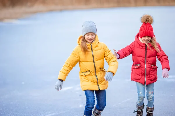 Adorable girls skating on ice rink outdoors in winter snow day — Stock Photo, Image