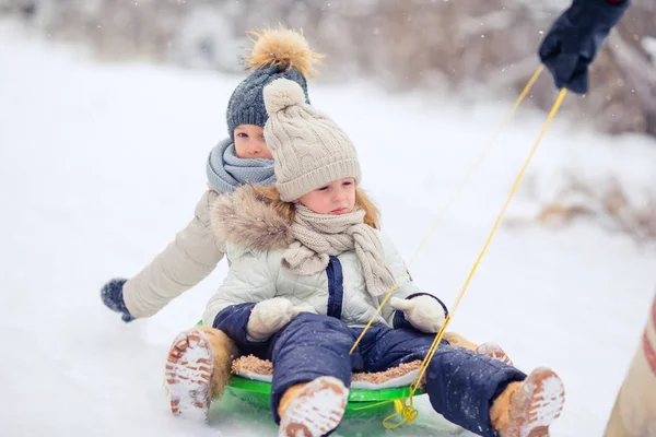 Adorable little happy girls sledding in winter snowy day. — Stock Photo, Image