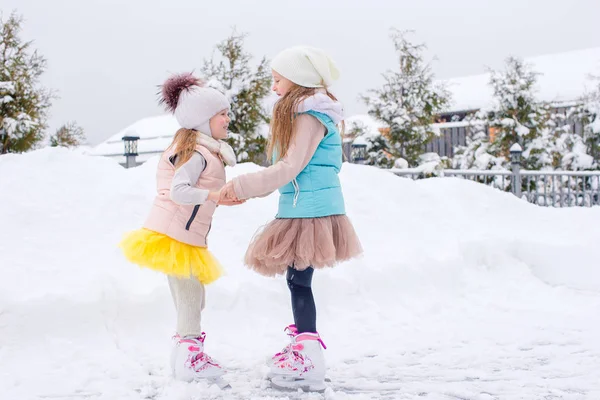 Adorable niñas patinaje en pista de hielo al aire libre en invierno día de nieve —  Fotos de Stock