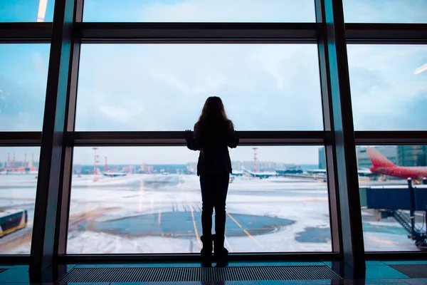 Klein meisje op de luchthaven in de buurt van groot raam, terwijl wachten op boarding — Stockfoto