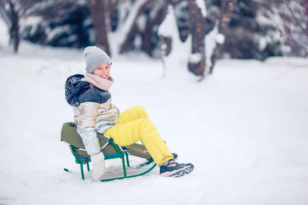 Adorable petite fille heureuse luge en hiver journée enneigée . — Photo