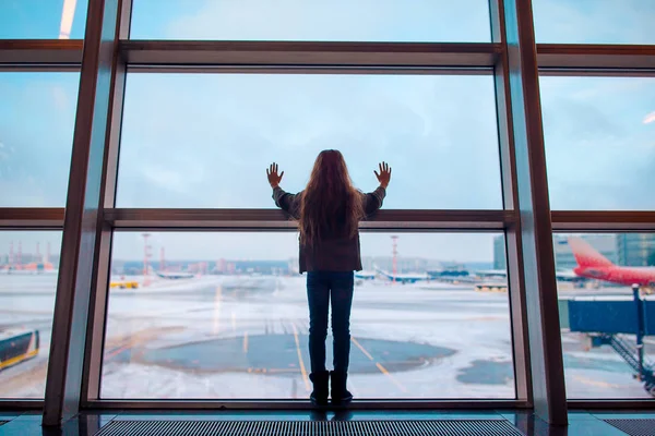 Kleines Mädchen am Flughafen in der Nähe eines großen Fensters, während es auf das Boarding wartet — Stockfoto