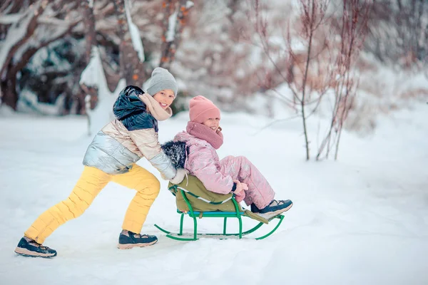 Adorable poco feliz niñas trineo en invierno nevado día . — Foto de Stock