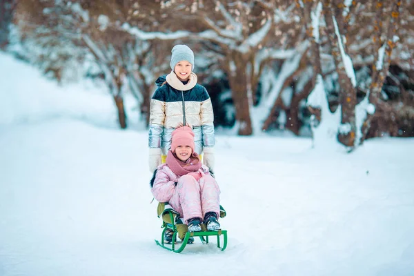 Adorable poco feliz niñas trineo en invierno nevado día . — Foto de Stock