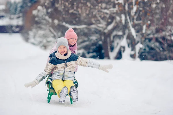 Adorable poco feliz niñas trineo en invierno nevado día . — Foto de Stock